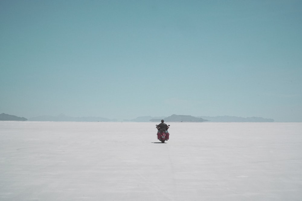 a person riding a snowmobile in a large flat area