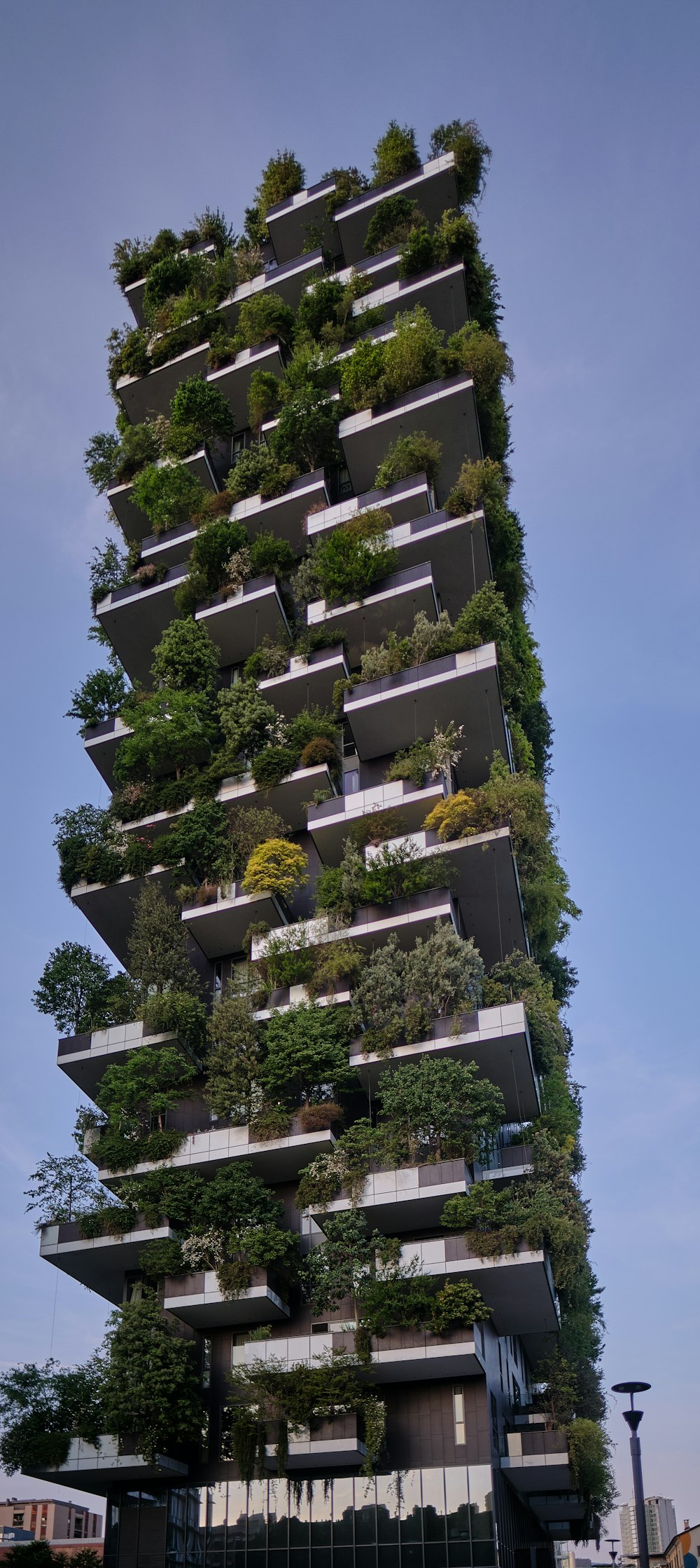 a tall building with many windows with Bosco Verticale in the background