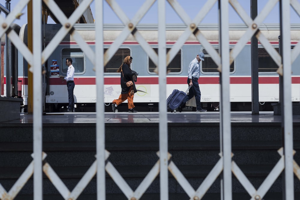 people with luggage walking on a train platform