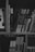 A collection of books arranged on a wooden bookshelf. The image is in black and white, highlighting the varied thickness and heights of the books. Some books have visible Chinese characters on their spines, suggesting they are in Chinese language.