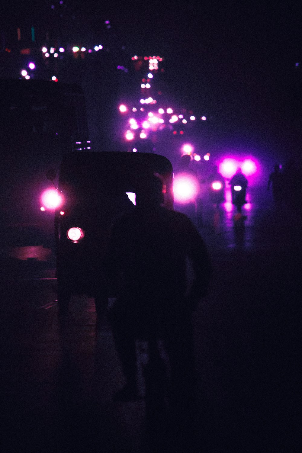 a person standing in front of a car with lights on it