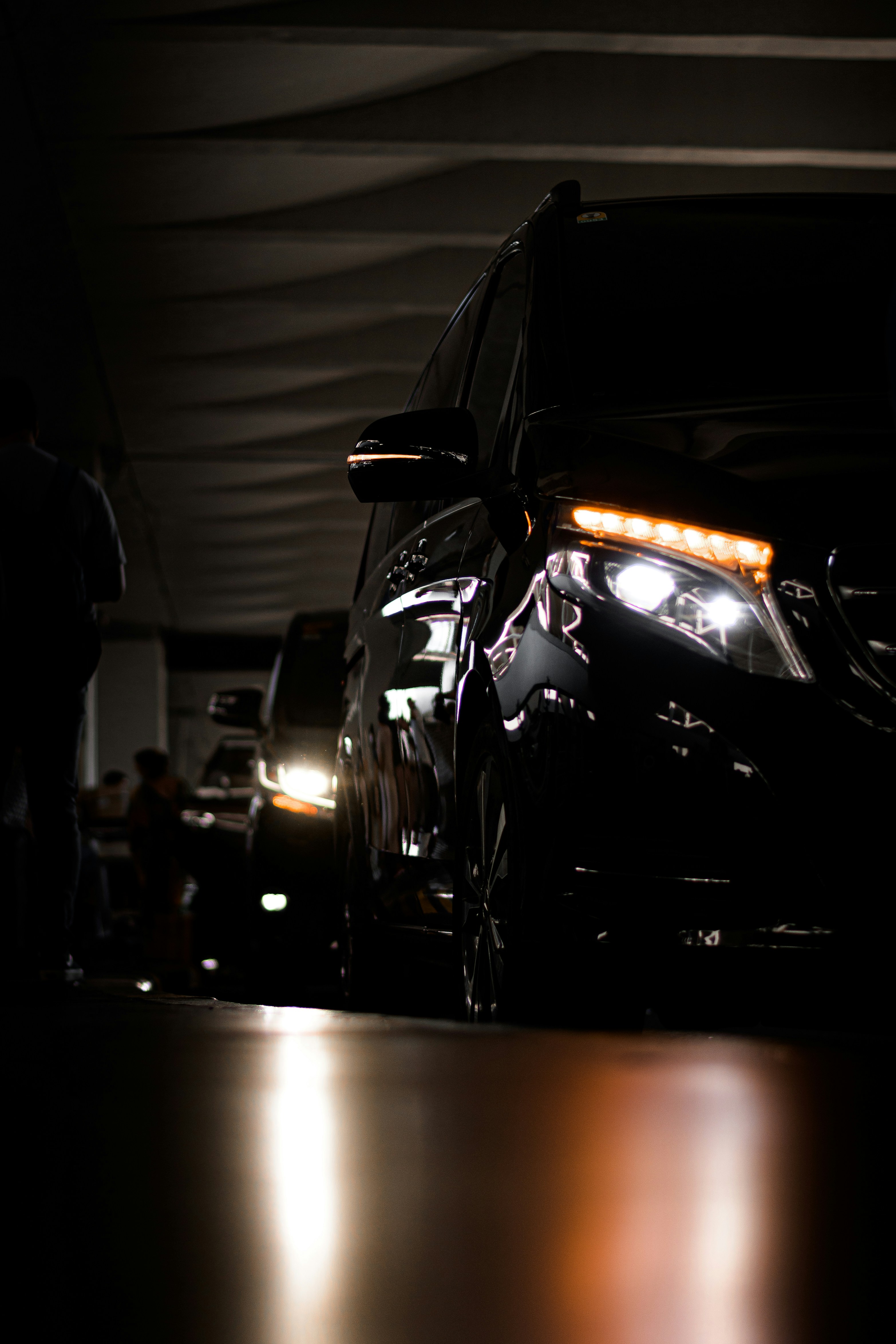 Dark Mercedes-Benz V-Class with its headlights on in a low-lit garage