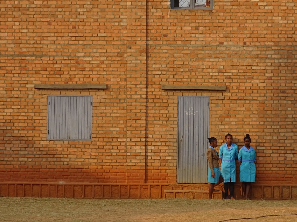 a group of women standing in front of a brick building