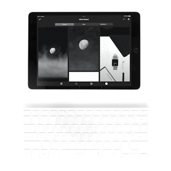 A tablet displaying a series of monochromatic images is placed above a white keyboard. The images on the tablet include a moon against a dark sky and a watch face, creating a modern, minimalist aesthetic. The keyboard appears faintly illuminated.