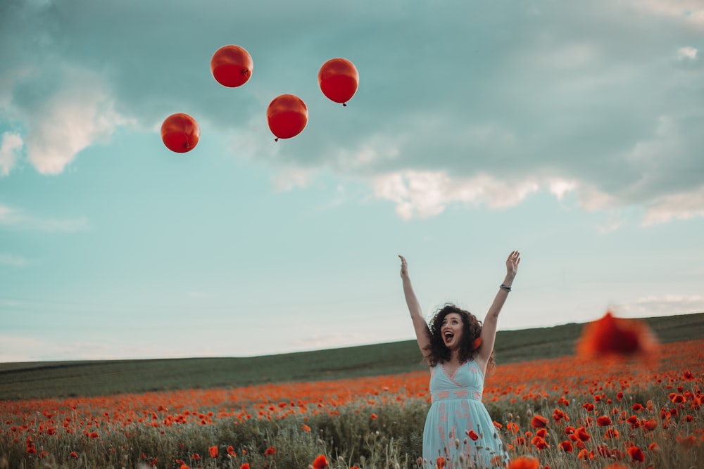 a man holding a bunch of red balloons in a field