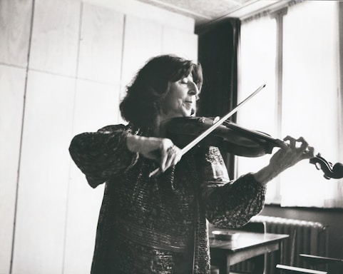 A violinist performing on stage under soft lighting in a classical concert hall.