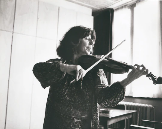 A violin student concentrating deeply during a private lesson, with golden light streaming through the window.