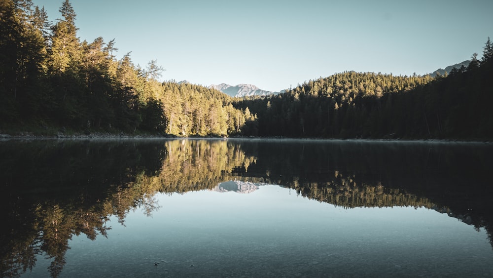 a lake with trees and mountains in the background