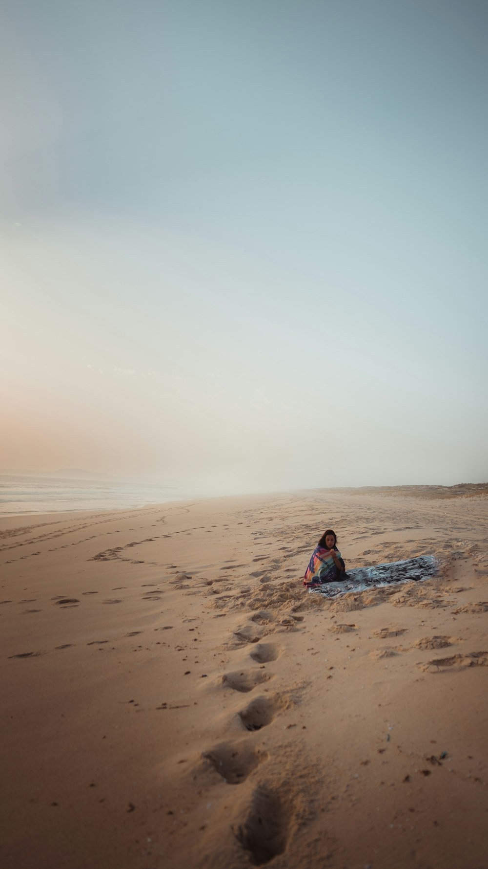 a person sitting on a surfboard on a beach