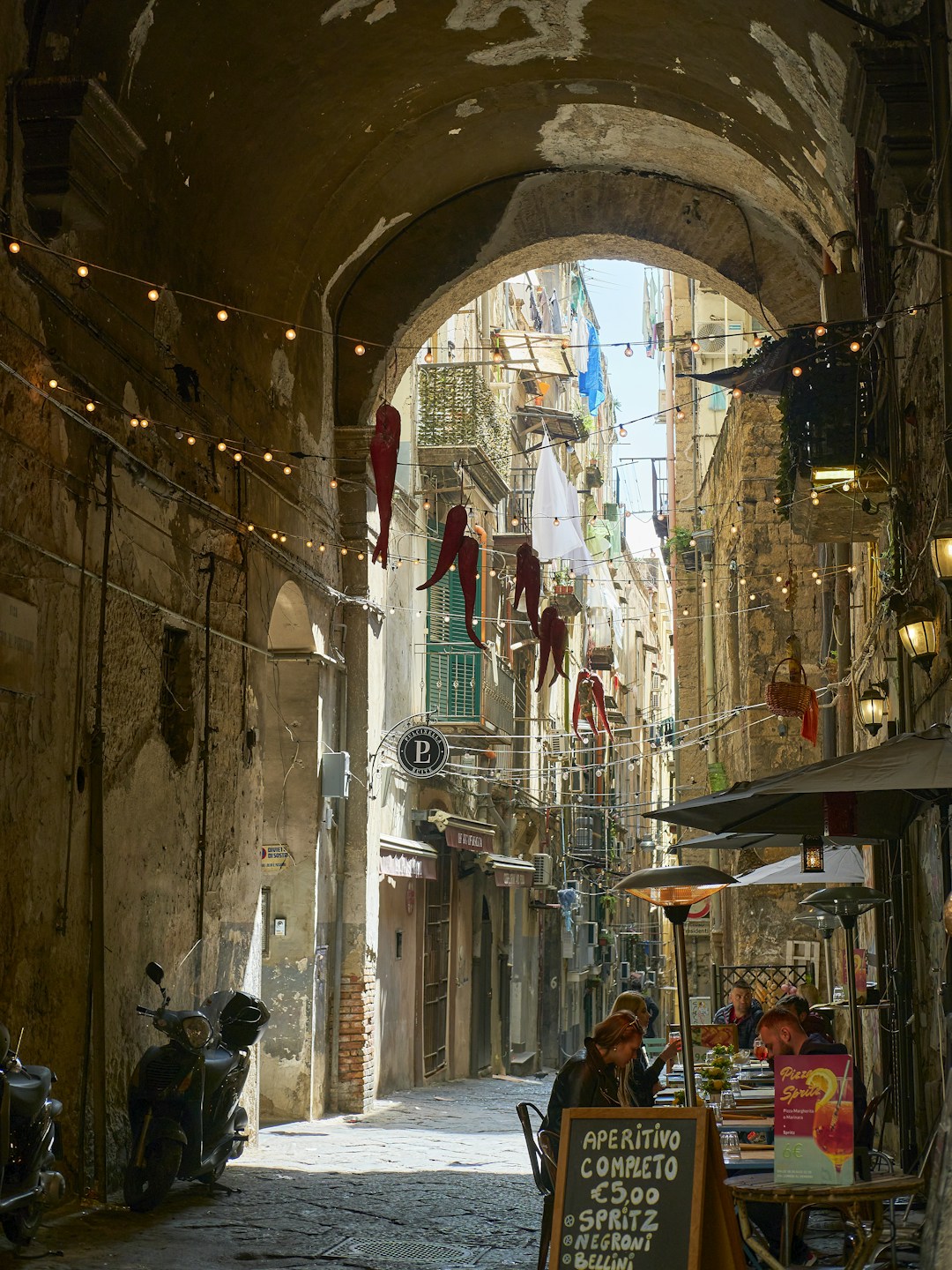 Naples - The sun-drenched, peeling yellow and ochre facades of a narrow street in Naples' historic center.