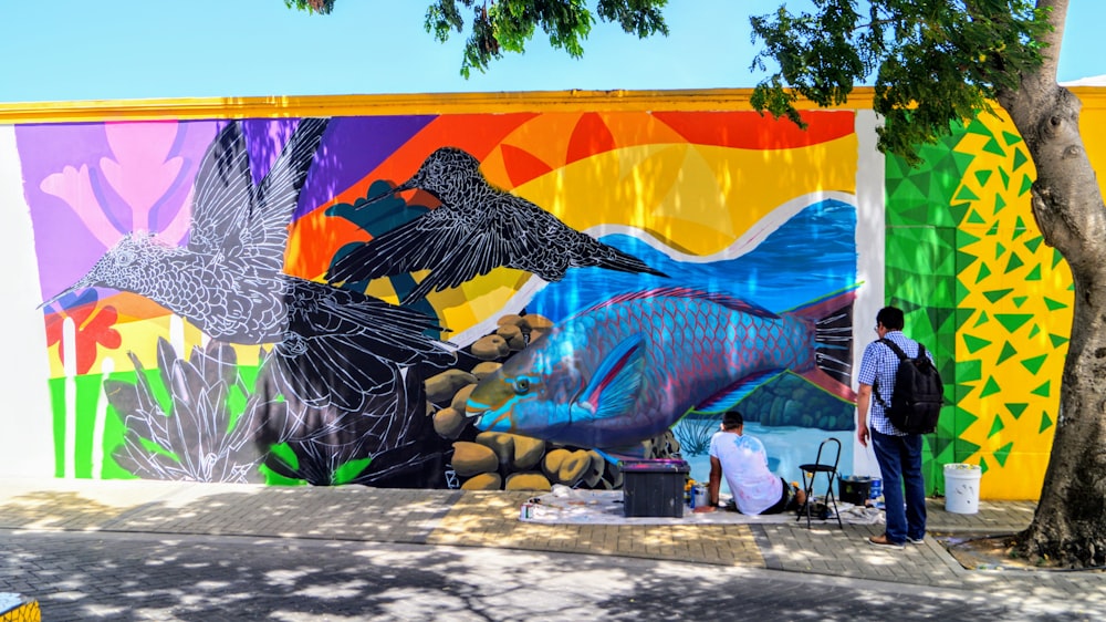 a couple of people looking at a mural of a bird