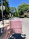 A happy customer holding a package in front of their doorstep on a sunny day.