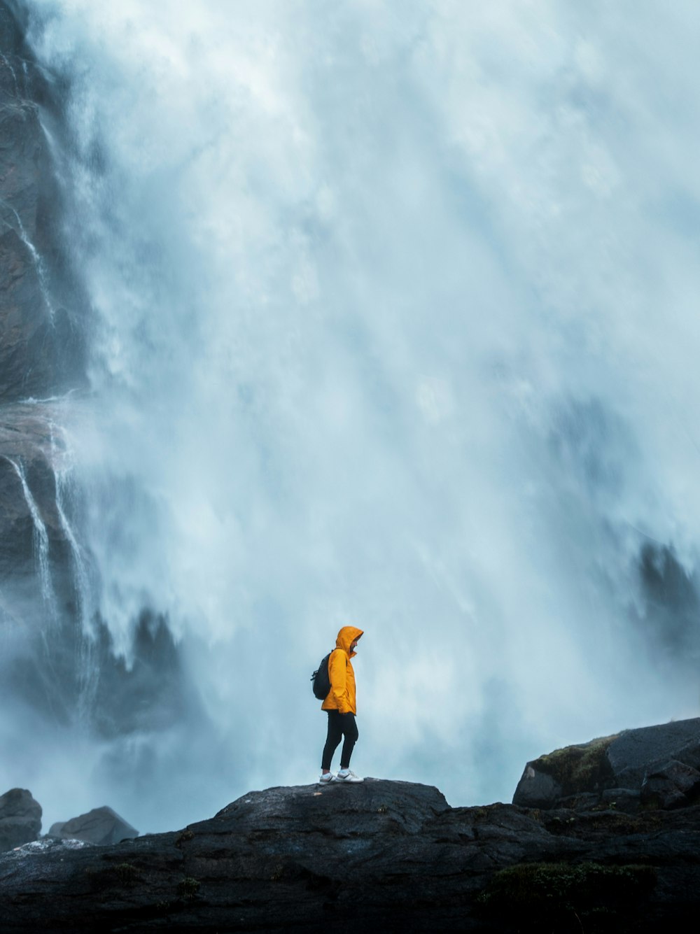 a person standing on a rock looking at a waterfall