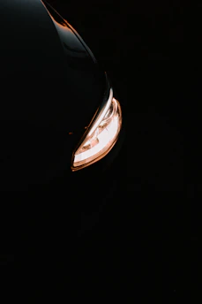 Close-up of a sleek, modern car headlight glowing brightly at dusk
