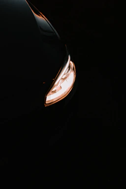 Close-up of a sleek, modified car front with sharp headlights glowing against a dark background.