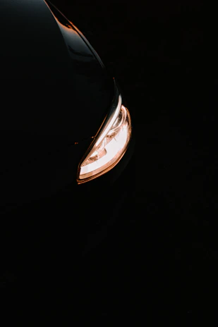 Close-up of a luxury car's glowing LED headlight cutting through the darkness with sharp focus