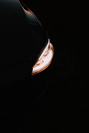 A close-up of a sleek auto lamp illuminating a dark road.