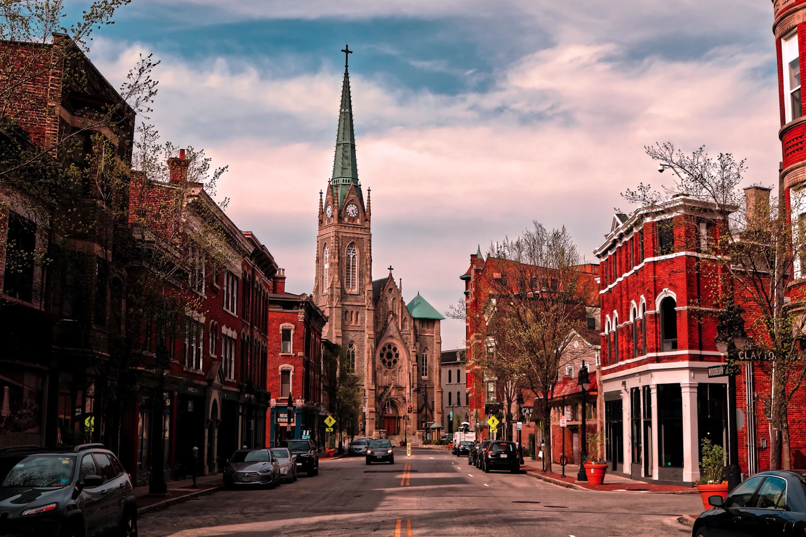 Brick storefronts and a church spire along an older downtown street.