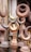 A collection of metal finials, predominantly featuring a crescent shape, displayed closely together. The items are made from different metals, showing a variety of tones from rusted brown to a brass-like gold. The setting suggests an outdoor market or a storage space.