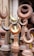 A collection of metal finials, predominantly featuring a crescent shape, displayed closely together. The items are made from different metals, showing a variety of tones from rusted brown to a brass-like gold. The setting suggests an outdoor market or a storage space.