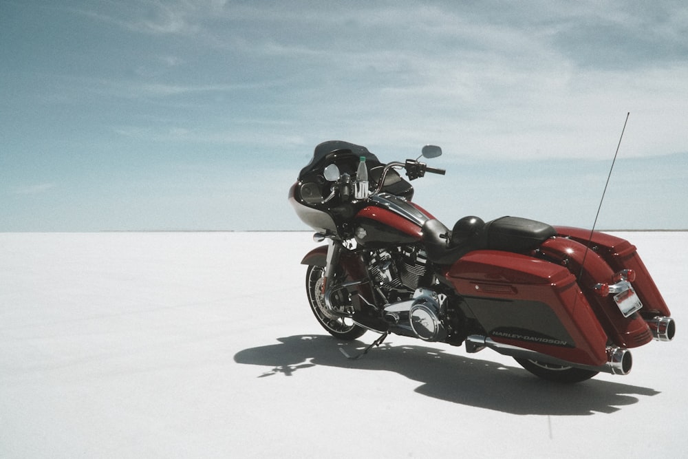 a red motorcycle parked on a sandy beach