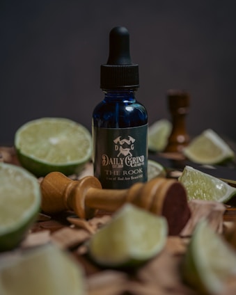A rugged man applying beard oil in a sunlit workshop filled with tools and wood shavings.