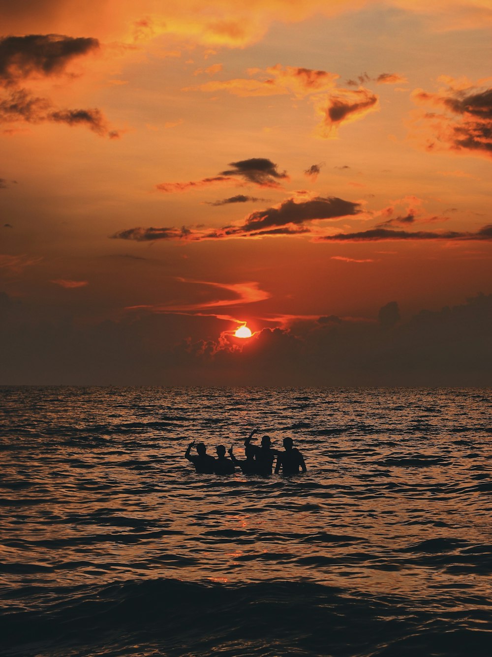 a group of people on a boat in the water with the sun setting