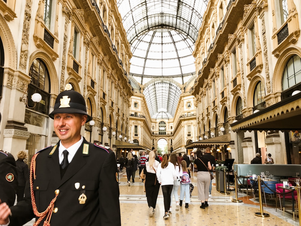 a person in a uniform in a large building with people walking around