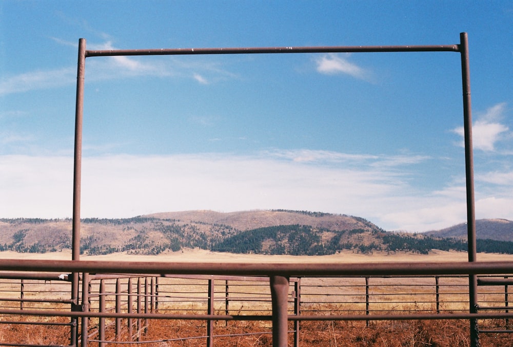 a fence with a view of a mountain range and blue sky