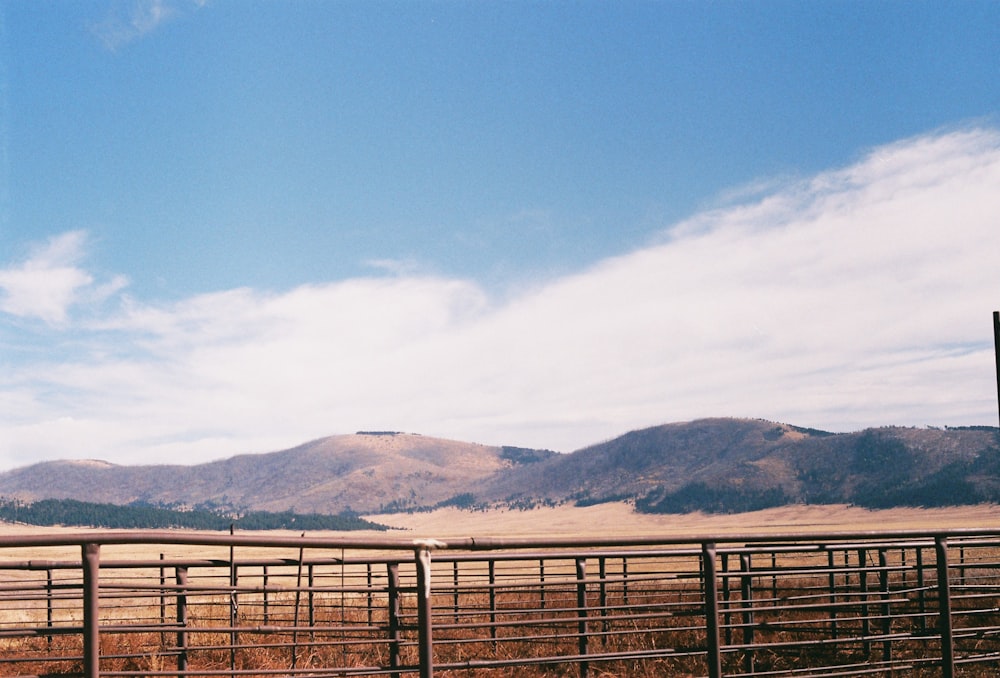 a fenced in field with mountains in the background