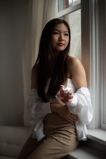 Woman applying perfume in a softly lit, sophisticated setting.