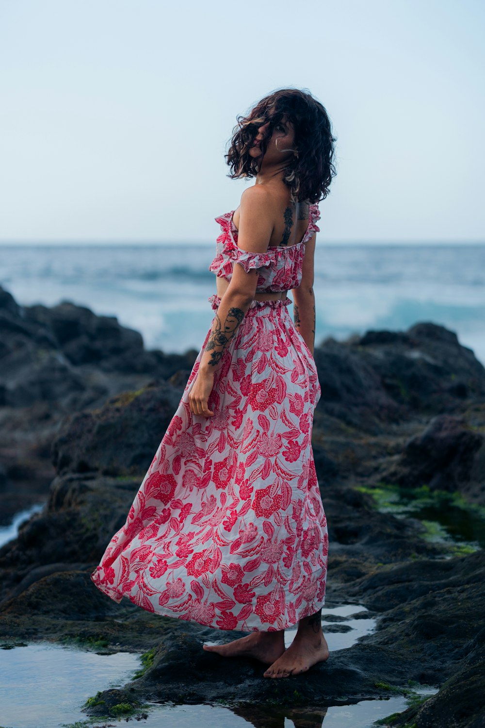 a person in a dress standing on a rocky beach