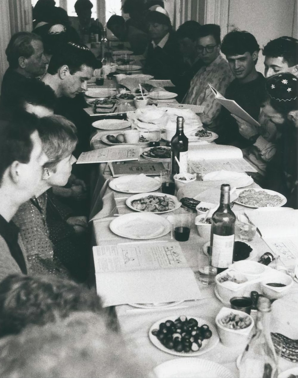 a group of people sitting at a table with food and drinks