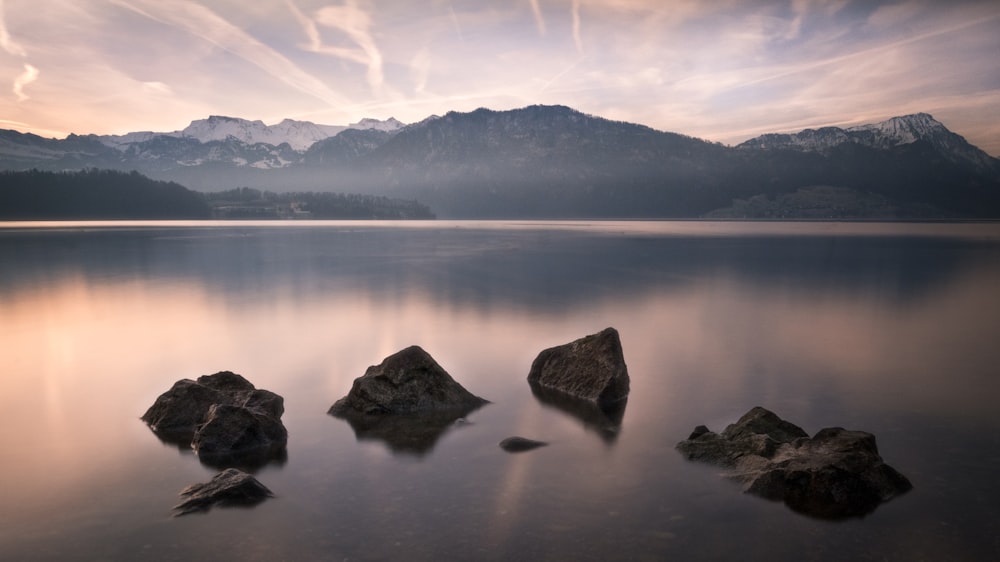 a body of water with rocks and mountains in the background