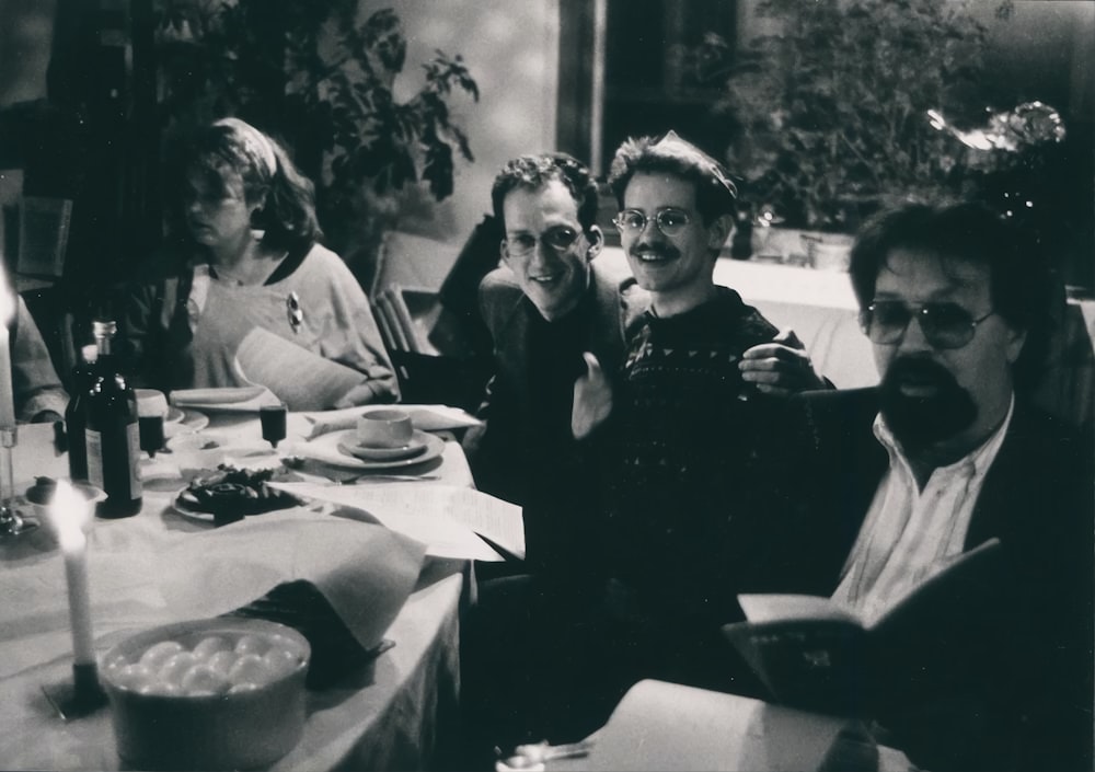 a group of people sitting at a table with food and drinks