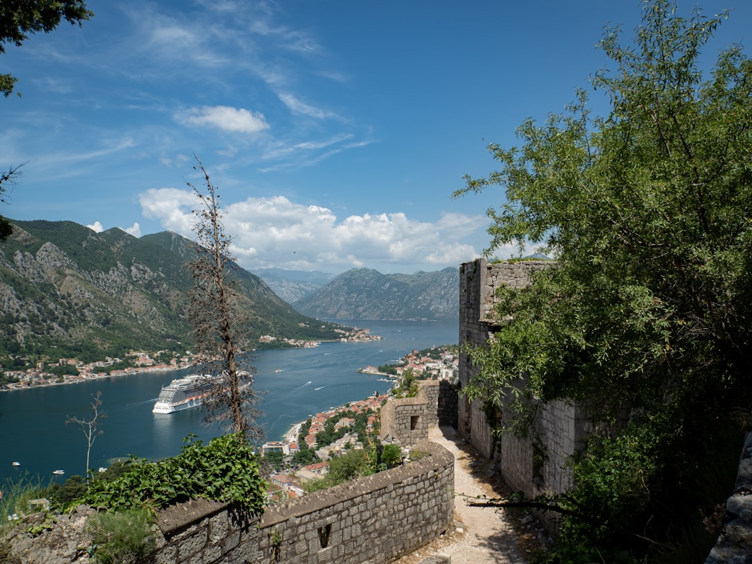 a stone wall with a body of water and mountains in the background,