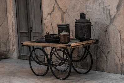 A rustic utility cart with wheels holding kitchen essentials in a bright kitchen.