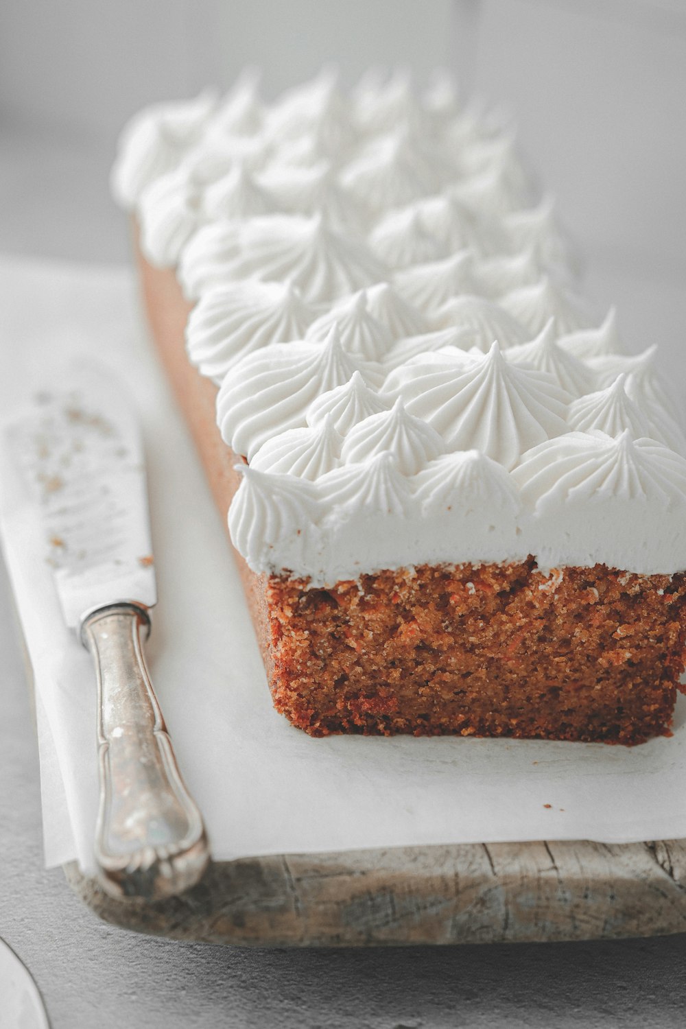 a slice of cake with white frosting on a cutting board