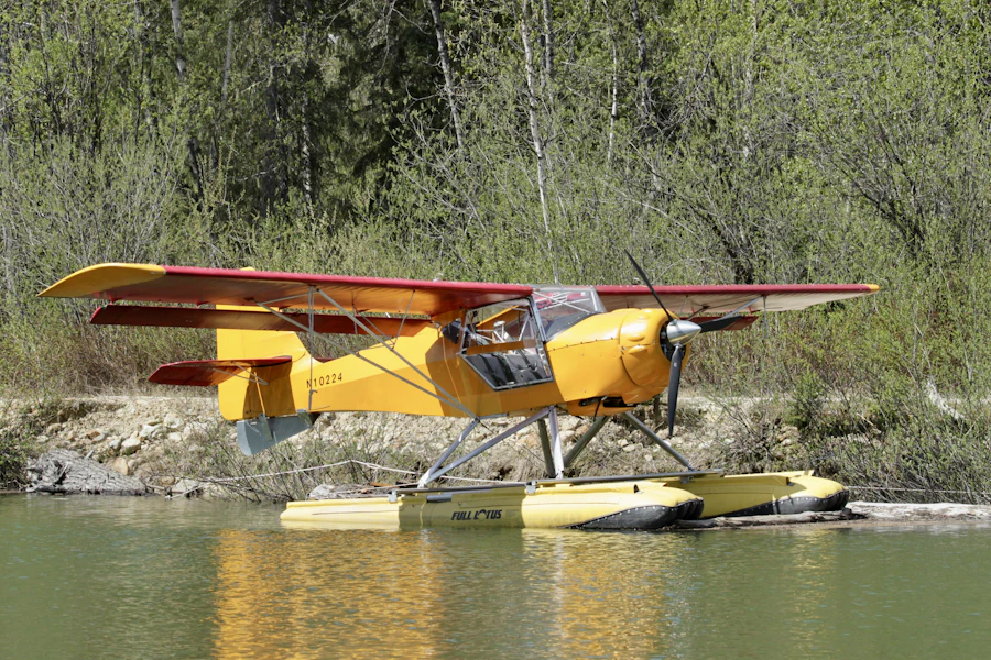 Yellow and red Super Cub float plane resting on a green shelf beside a river mouth