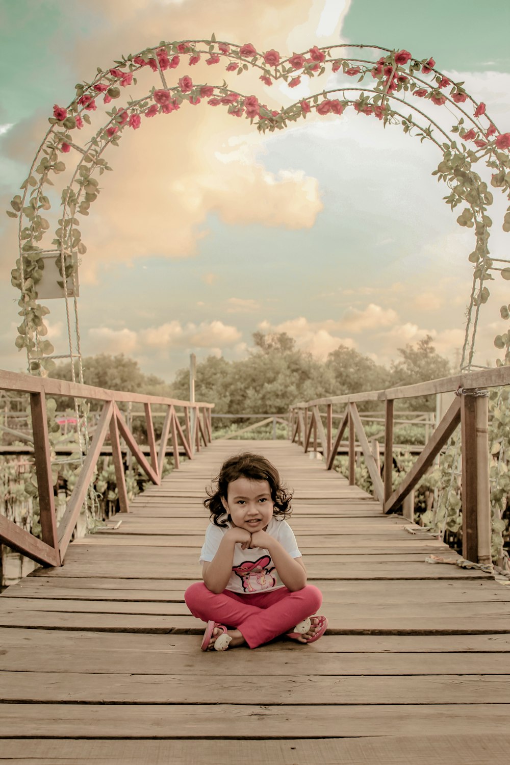 a girl sitting on a wooden bridge