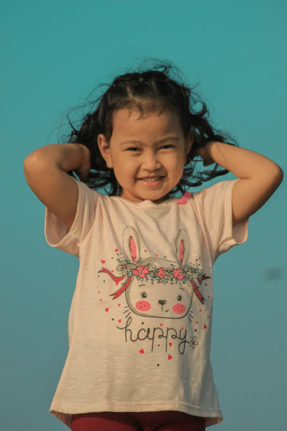 a young girl with her hair pulled back and her hands on her head