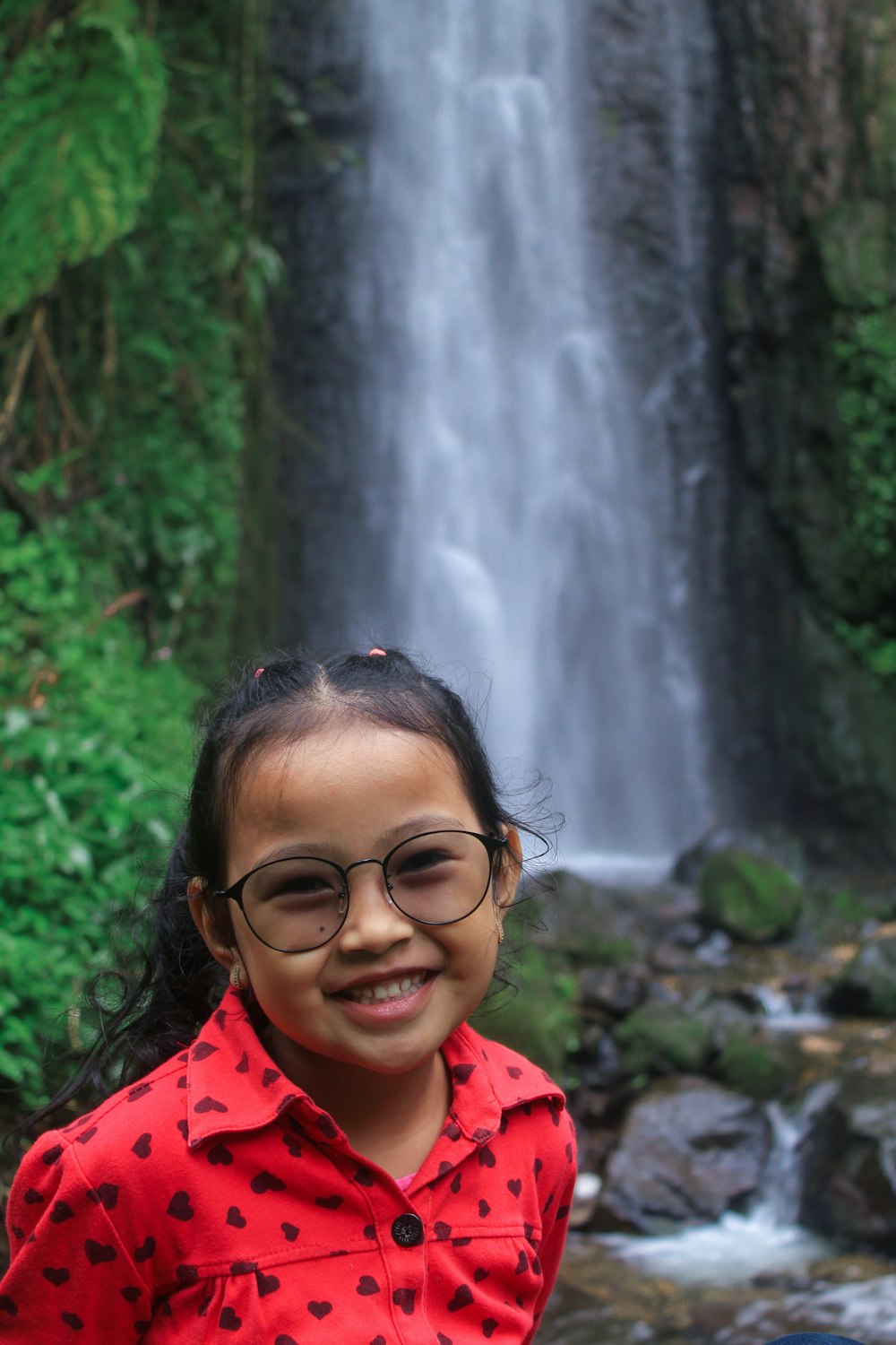 a person smiling in front of a waterfall