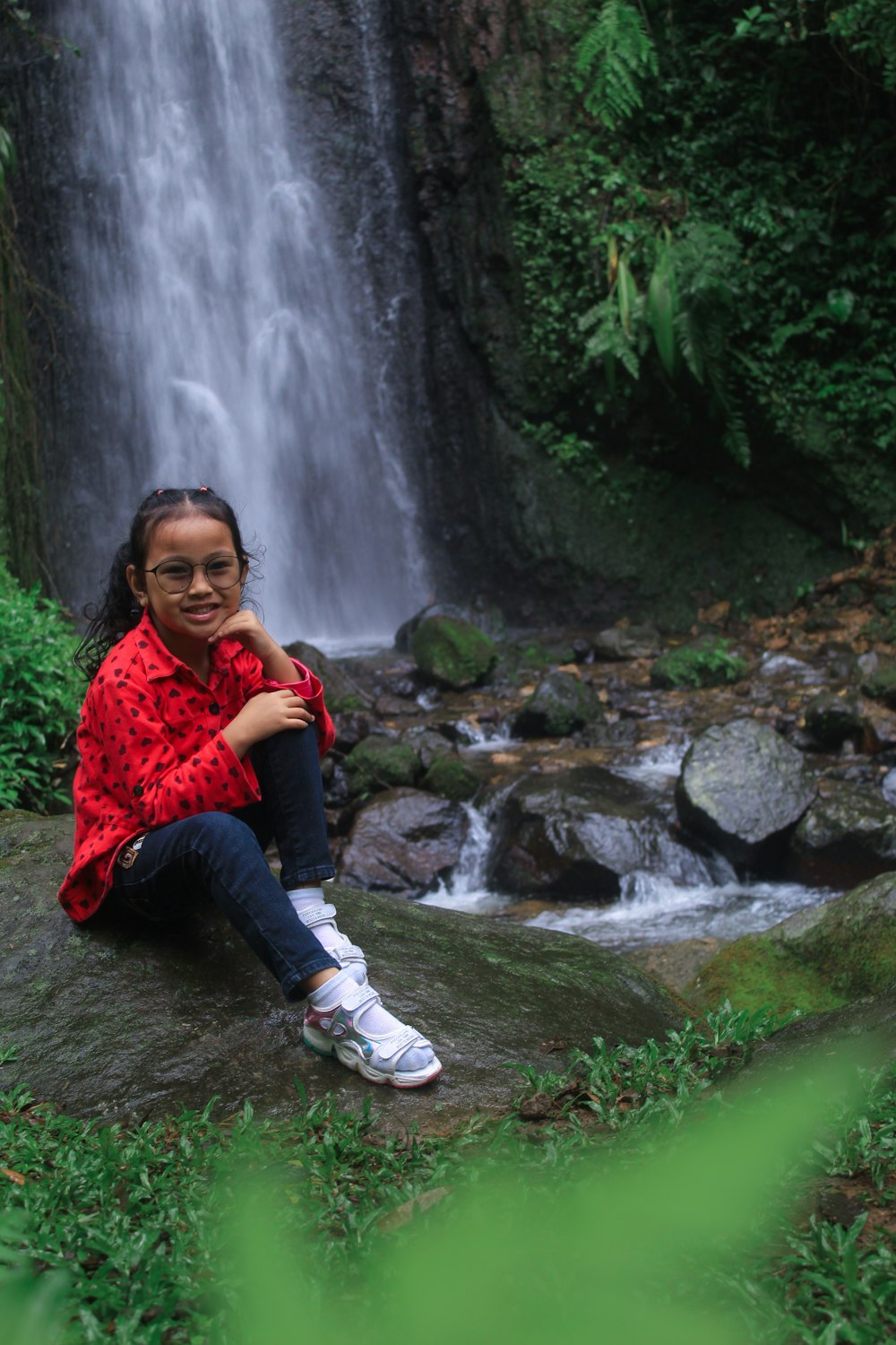 Eine Person, die auf einem Felsen an einem Wasserfall sitzt