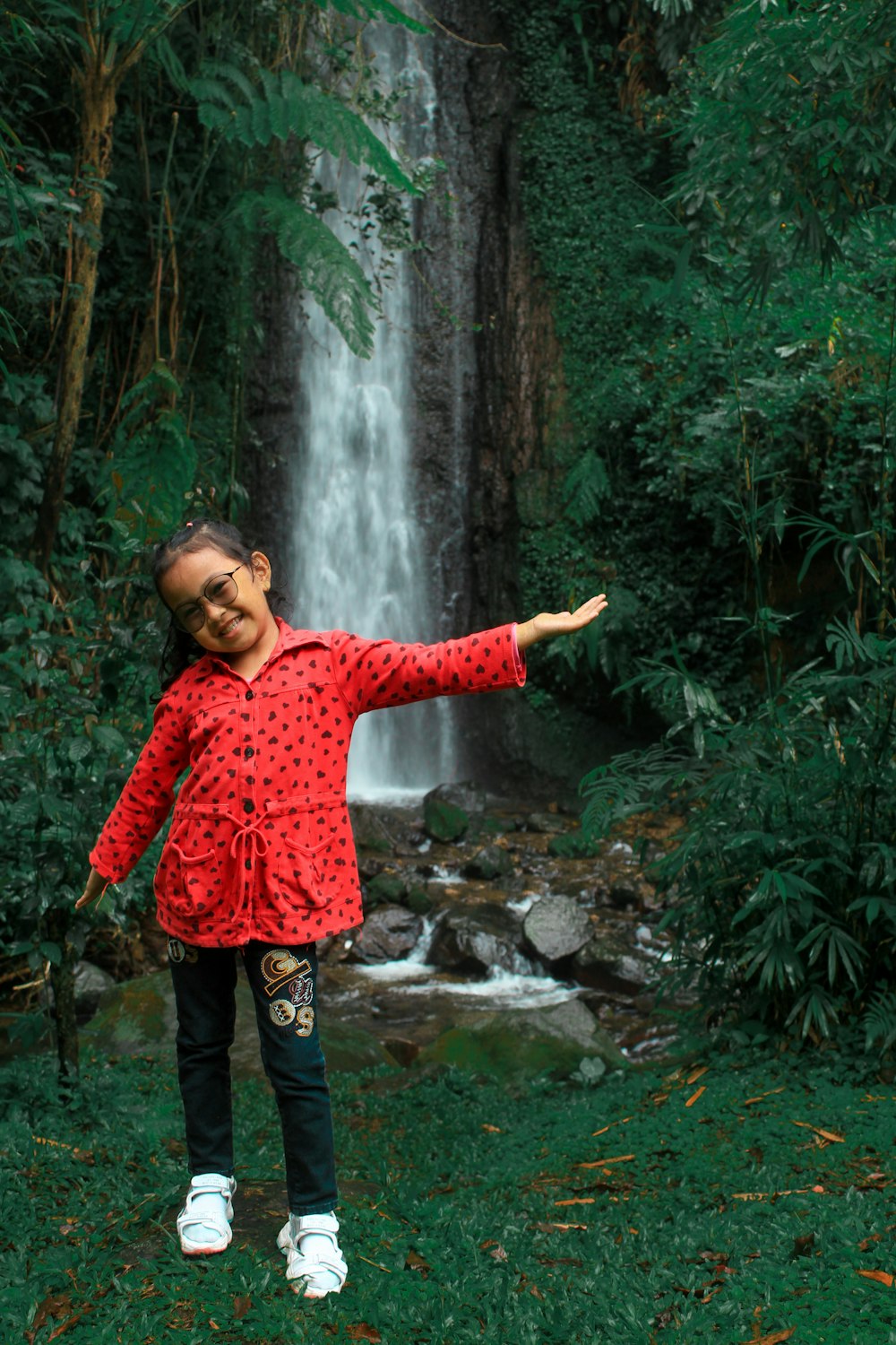 a person posing in front of a waterfall