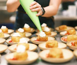 A professional pastry chef demonstrating cake decorating techniques.