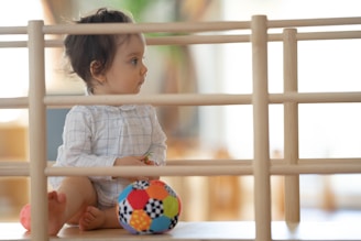 A happy toddler safely playing behind a sturdy door barrier in a cozy home setting.