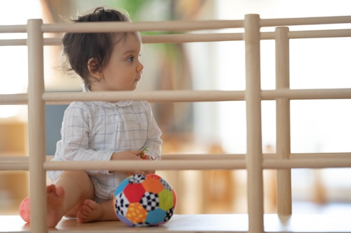 A happy toddler safely playing behind a sturdy door barrier in a cozy home setting.