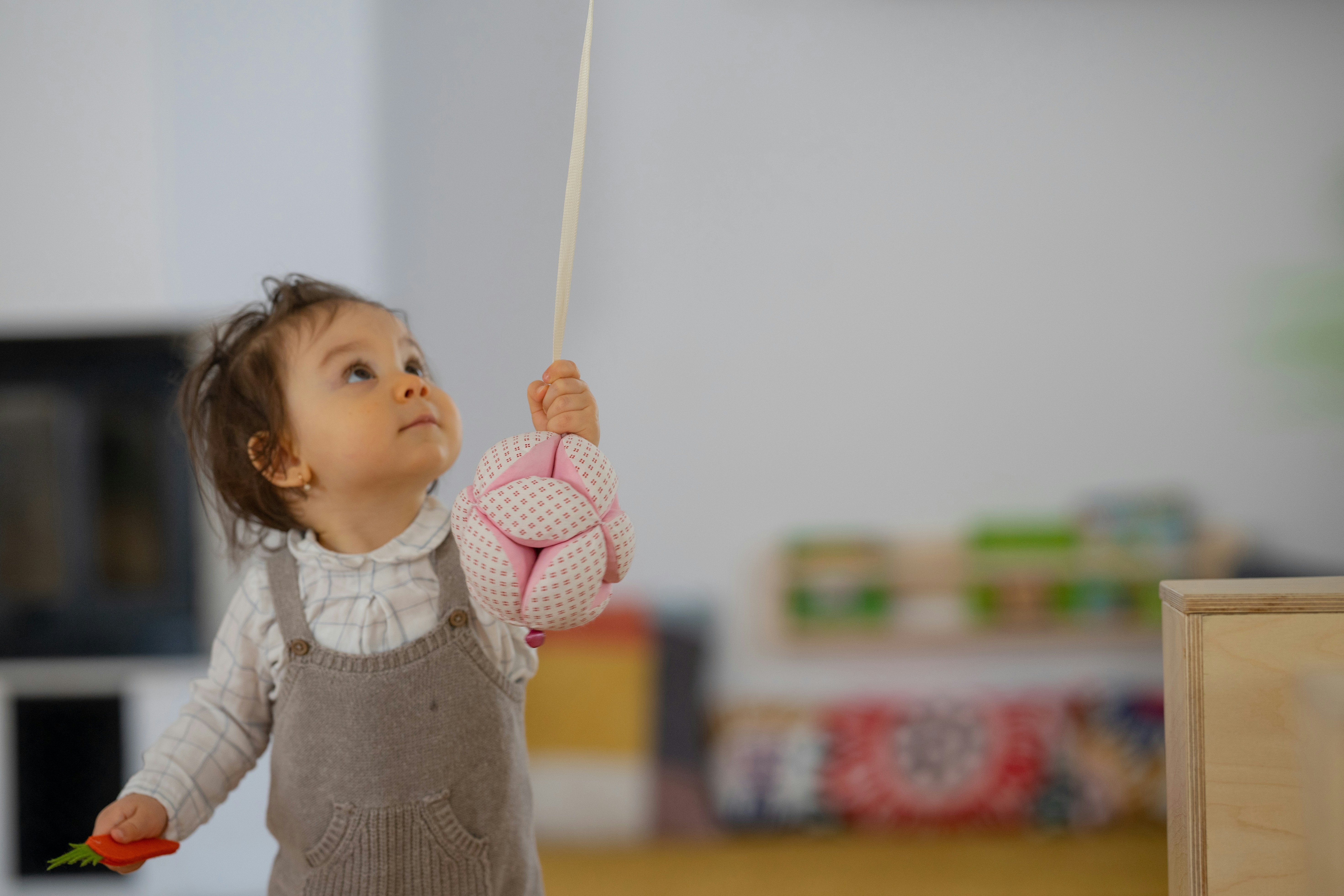 a little girl holding a pink toy