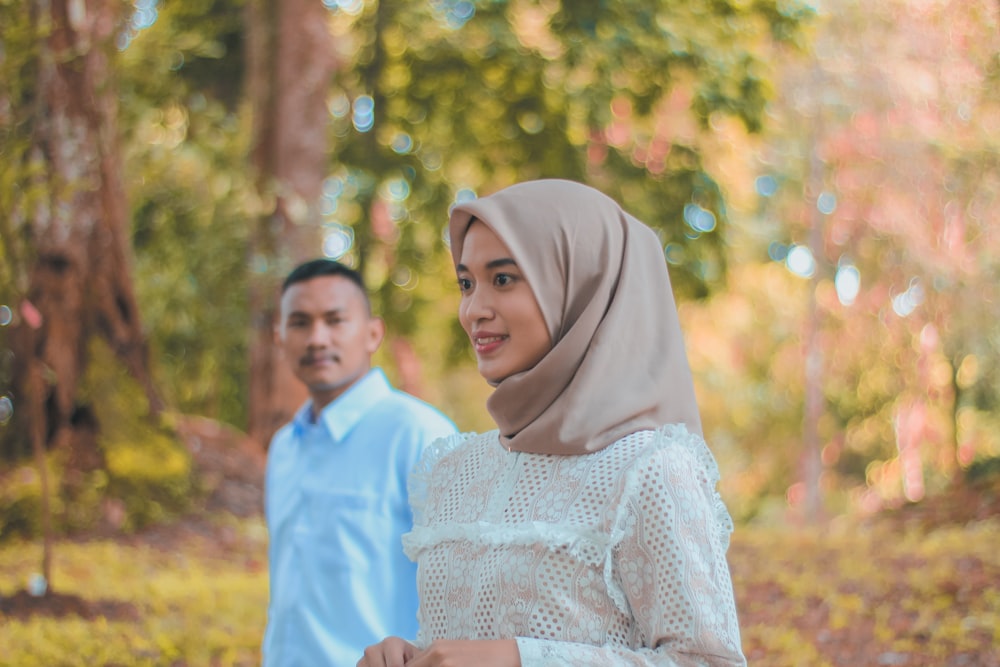 a man and woman standing in a forest