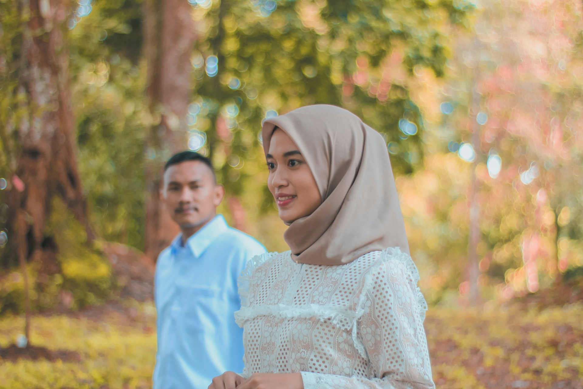 a man and woman standing in a forest